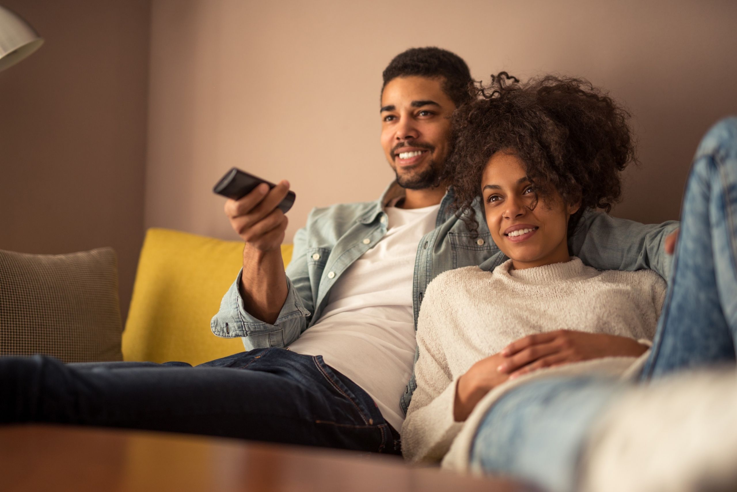 A young couple watching television at home